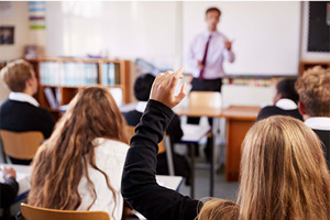 School classroom with teacher at front and children facing the board.