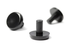 Small black plastic pegs used as buffers between stacking chairs. Three at varying angles.