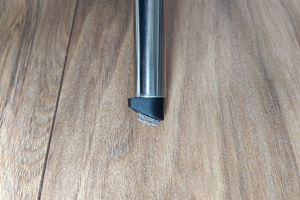 Top-down view of a round black LDPE injection-moulded foot insert fitted to the end of a metal tube leg, with a felted angled base profile visible.