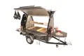 Mobile BBQ trailer in use with visible red PVC handle grip on the front tow bar.