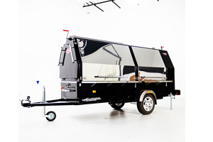 Side view of a closed mobile BBQ trailer with three visible red PVC dip moulded handle grips on top and side panels, emphasizing their straight-sided, flexible construction.