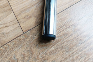 Top-down view of a black round injection-moulded insert foot fitted to the base of a metal tube leg.