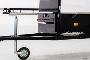 Side view of a mobile BBQ unit with a close-up on the tow bar area, featuring a red PVC dip moulded handle grip mounted on a vertical black panel, highlighting its straight-sided, flexible design.