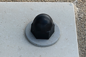 Angled front-top view of a domed, black LDPE injection moulded nut and bolt cap mounted over a grey metal fastener.