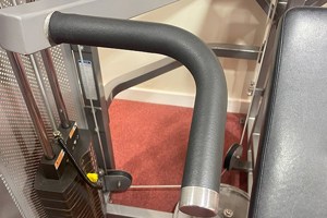 Close-up of a gym machine arm featuring a black, textured PVC dip moulded sleeve with a straight and curved profile, fitted over a metal handle for enhanced grip and comfort.