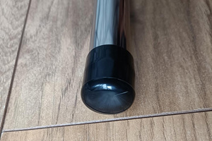 A metal pole chair leg with a black glossy plastic chair foot mounted to the base.