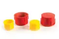 Angled view of four plastic threaded caps in red and yellow—two shown upright and two facing down.
