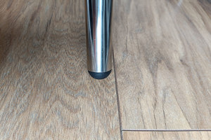 Top-down view of a round black injection-moulded foot insert fitted to the end of a metal tube leg, with an domed base profile visible.