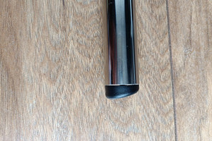 Top-down view of a round black injection-moulded foot insert fitted to the end of a metal tube leg, with an angled base profile visible.