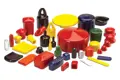 Angled view of a large assortment of flexible PVC dip moulded caps and plugs in a wide range of colours, shapes, and sizes, arranged together on a white background.