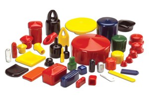 Angled view of a large assortment of flexible PVC dip moulded caps and plugs in a wide range of colours, shapes, and sizes, arranged together on a white background.