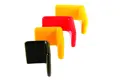 Angled view of four flexible PVC dip moulded angle caps—two yellow, one red, and one black.